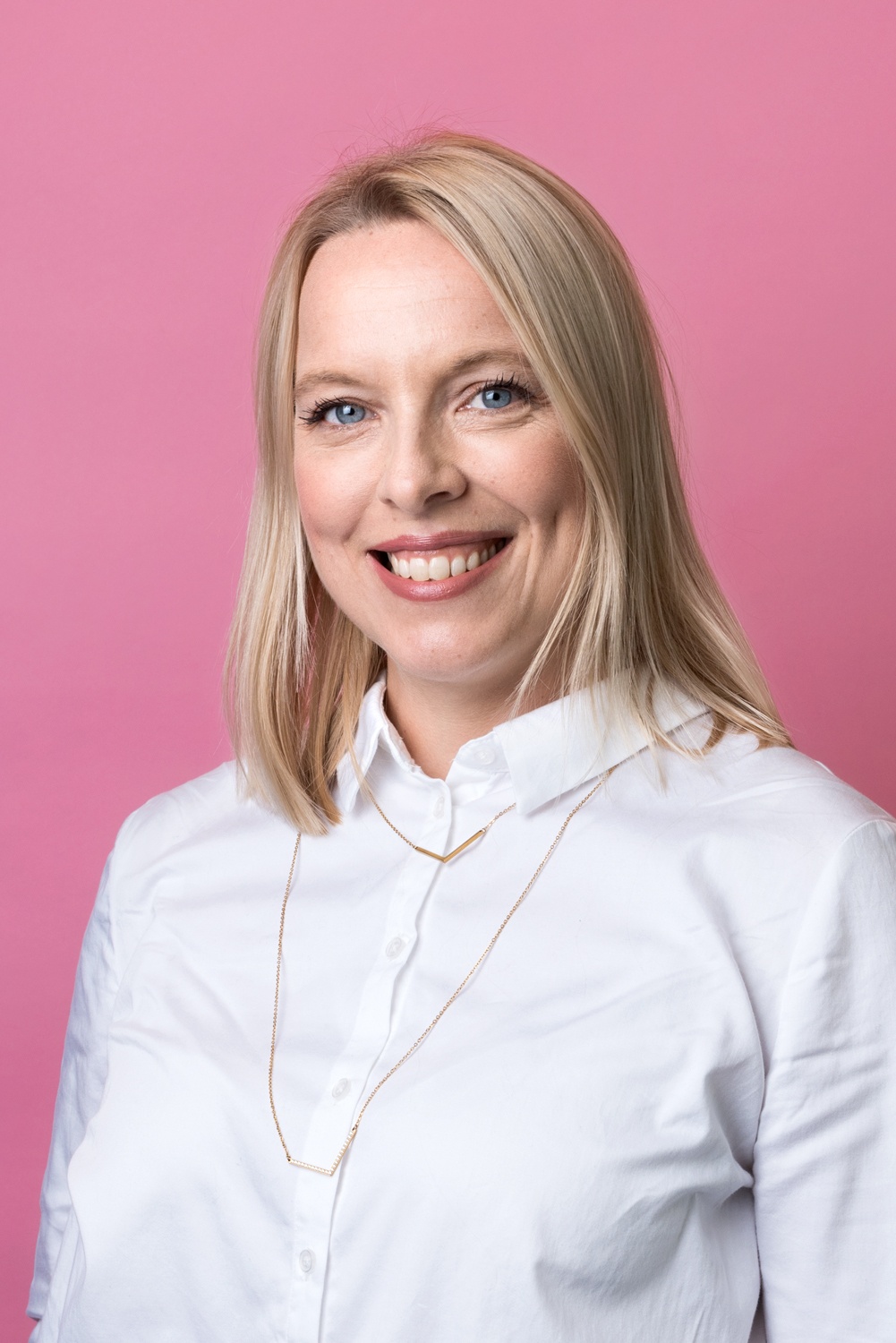 Porträttbild Johanna Winbladh. Johanna har mellanlångt, rakt blont hår. Hon bär en vit skjorta och ett guldhalsband.