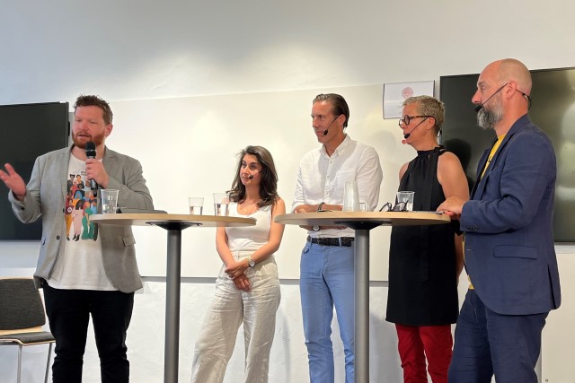 På bilden syns en moderator samt fyra personer i en paneldiskussion.