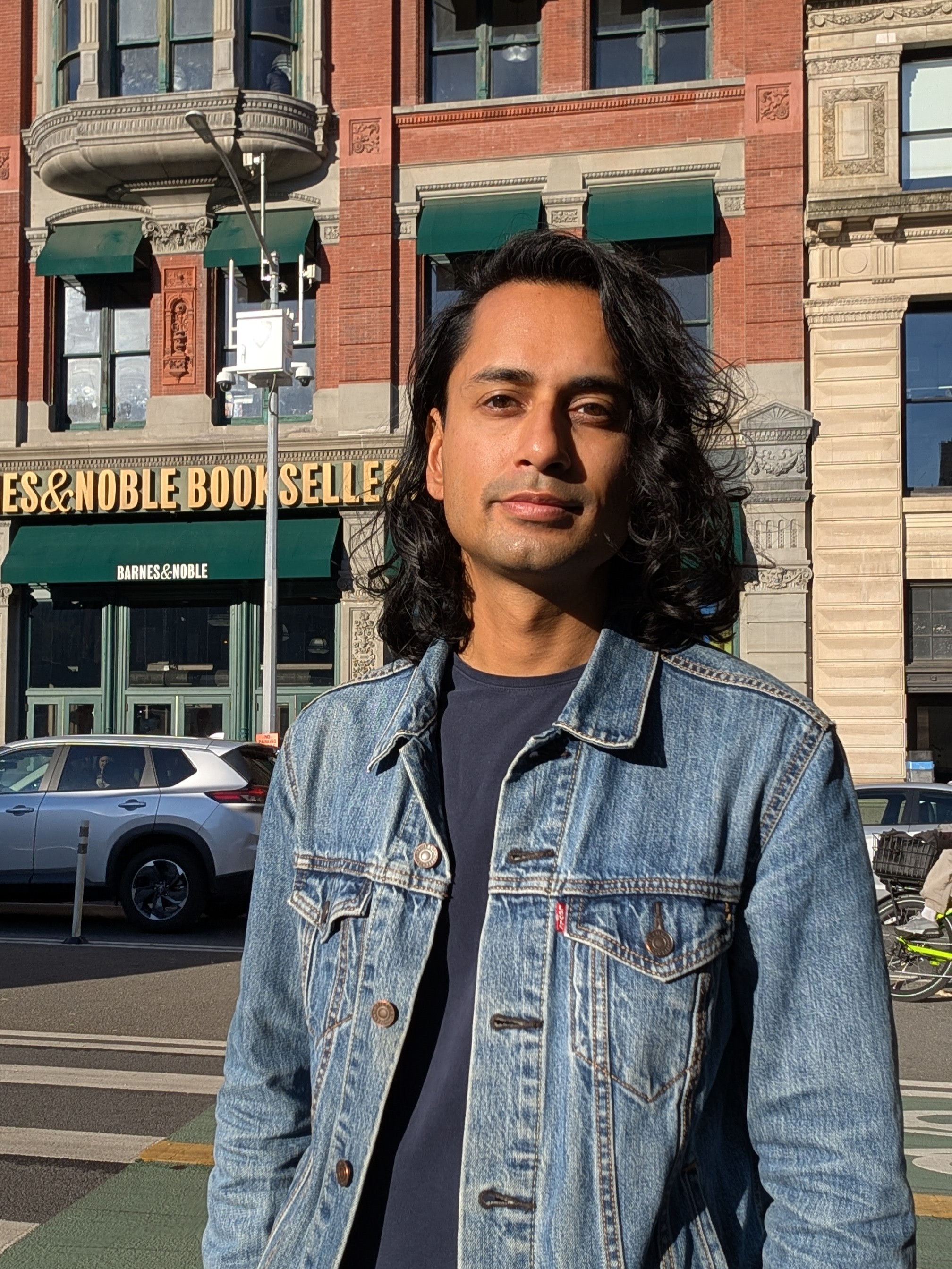 Tanvir står i New York framför en bokaffär, det är soligt ute.