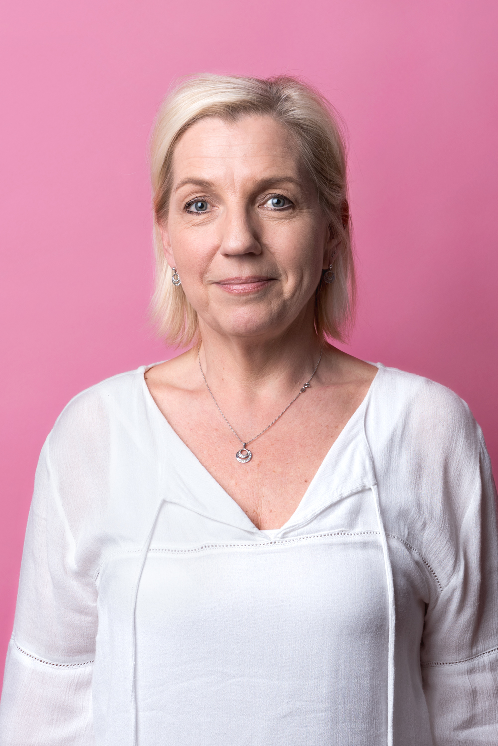 Porträttbild Lena Eriksson. Lena har en vit blus på sig och tittar rakt in i kameran med allvarlig blick.