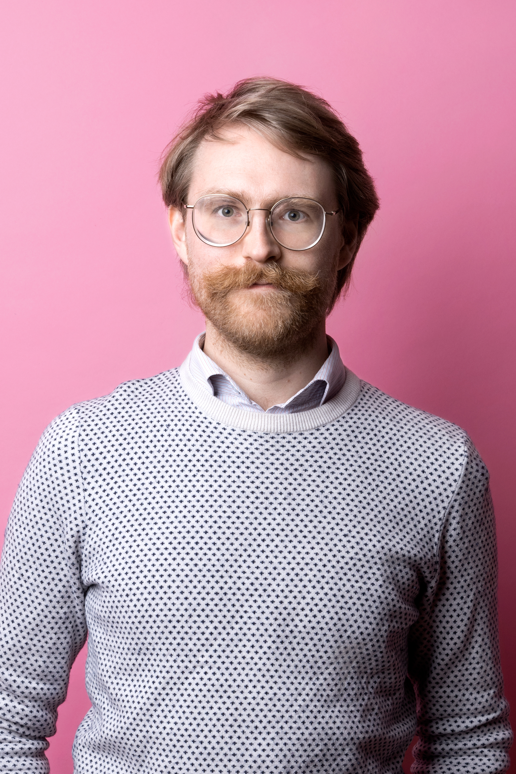 Porträttbild David Dahlborn. David har rödblont kort hår och mustasch. Han bär en ljus skjorta och tröja, och ljusa glasögon.