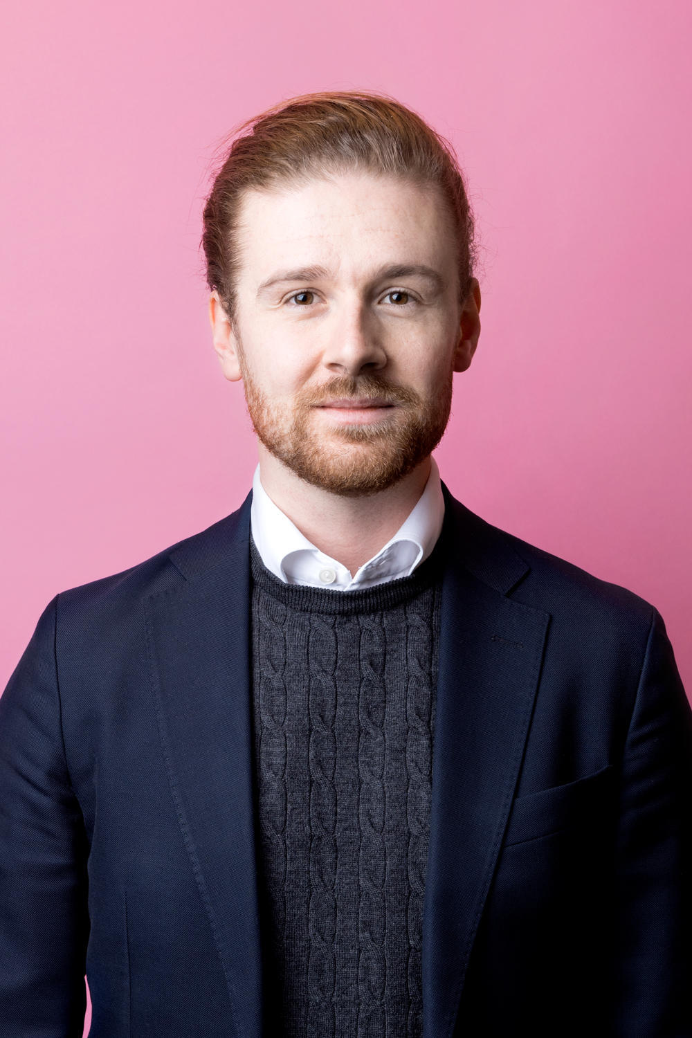 Porträttbild Jesper Skalberg Karlsson. Jesper har rött hår uppsatt i tofs, han tittar rakt in i kameran med en allvarlig min.
