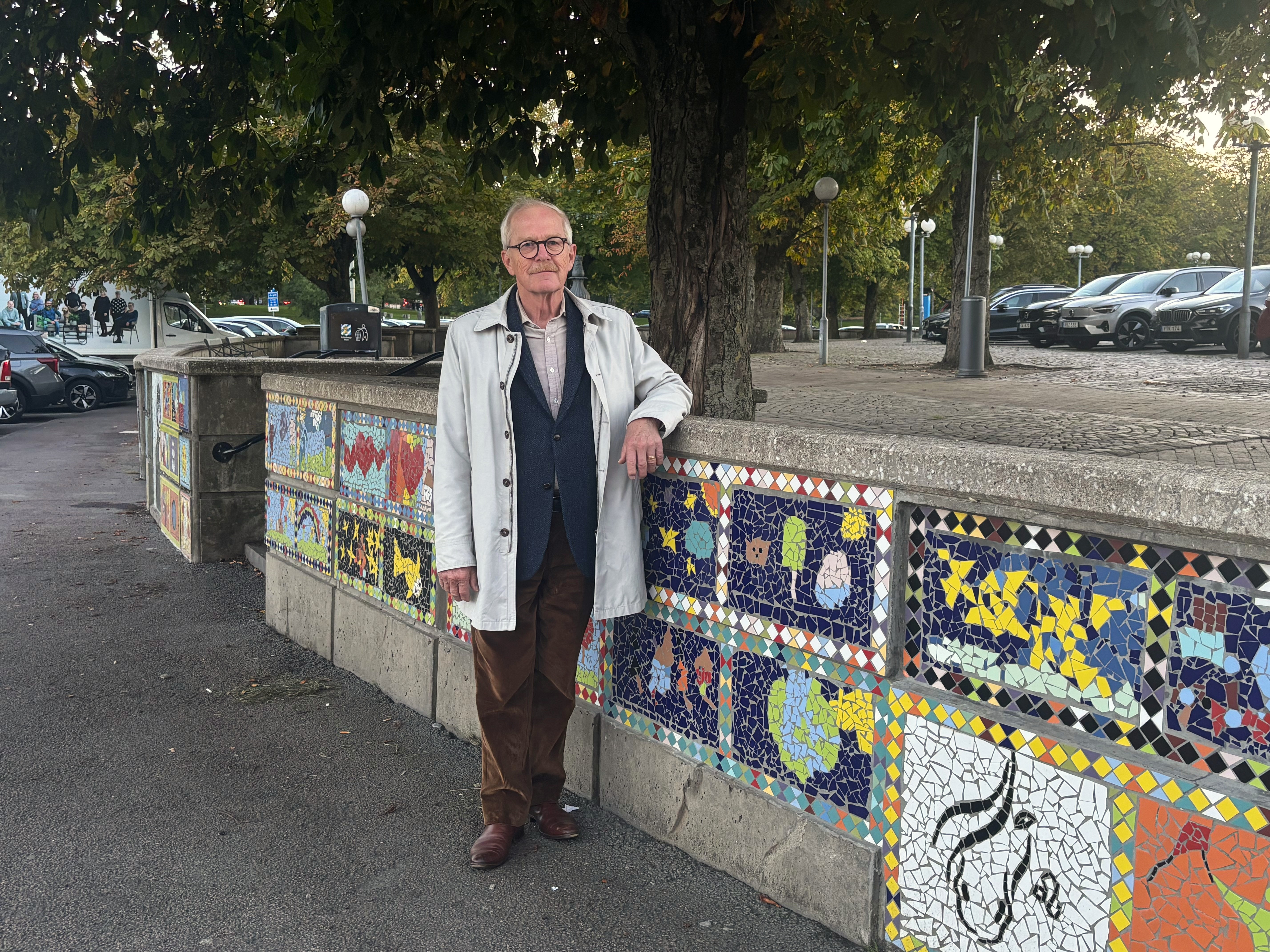 Erik Amnå står utomhus och lutar sig på en mur med mosaikmönster. Han tittar in i kameran med ett litet leende.