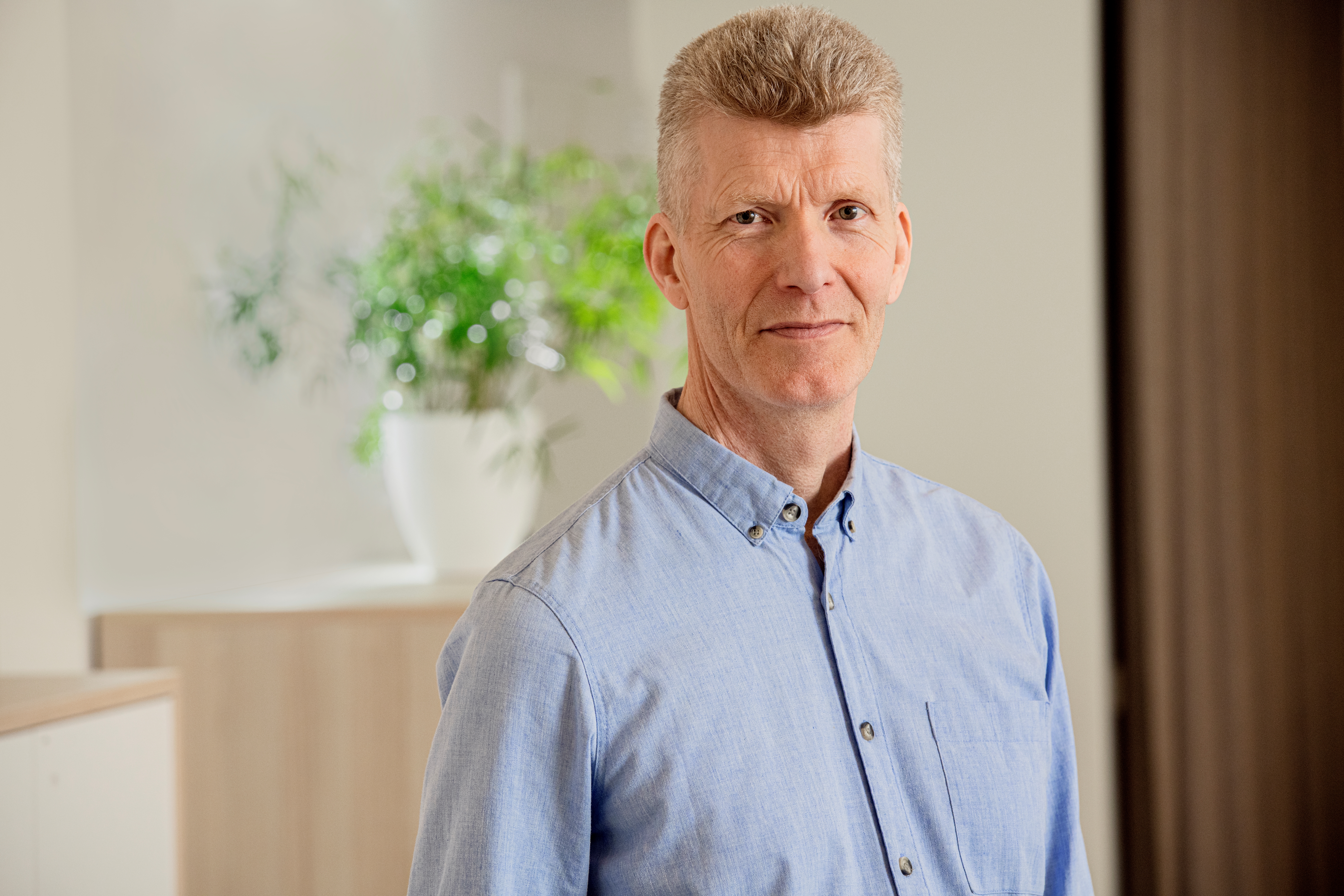 Porträttbild Jan Jonsson. Jan har en ljusblå skjorta på sig och tittar rakt in i kameran.