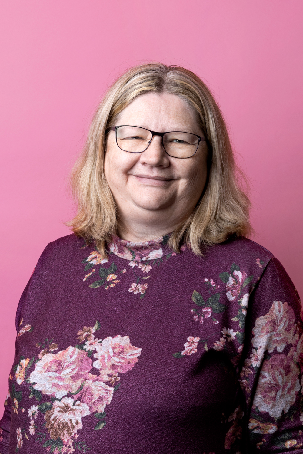 Porträttbild Annika Blom. Annika har en lila tröja med rosa blommor på.