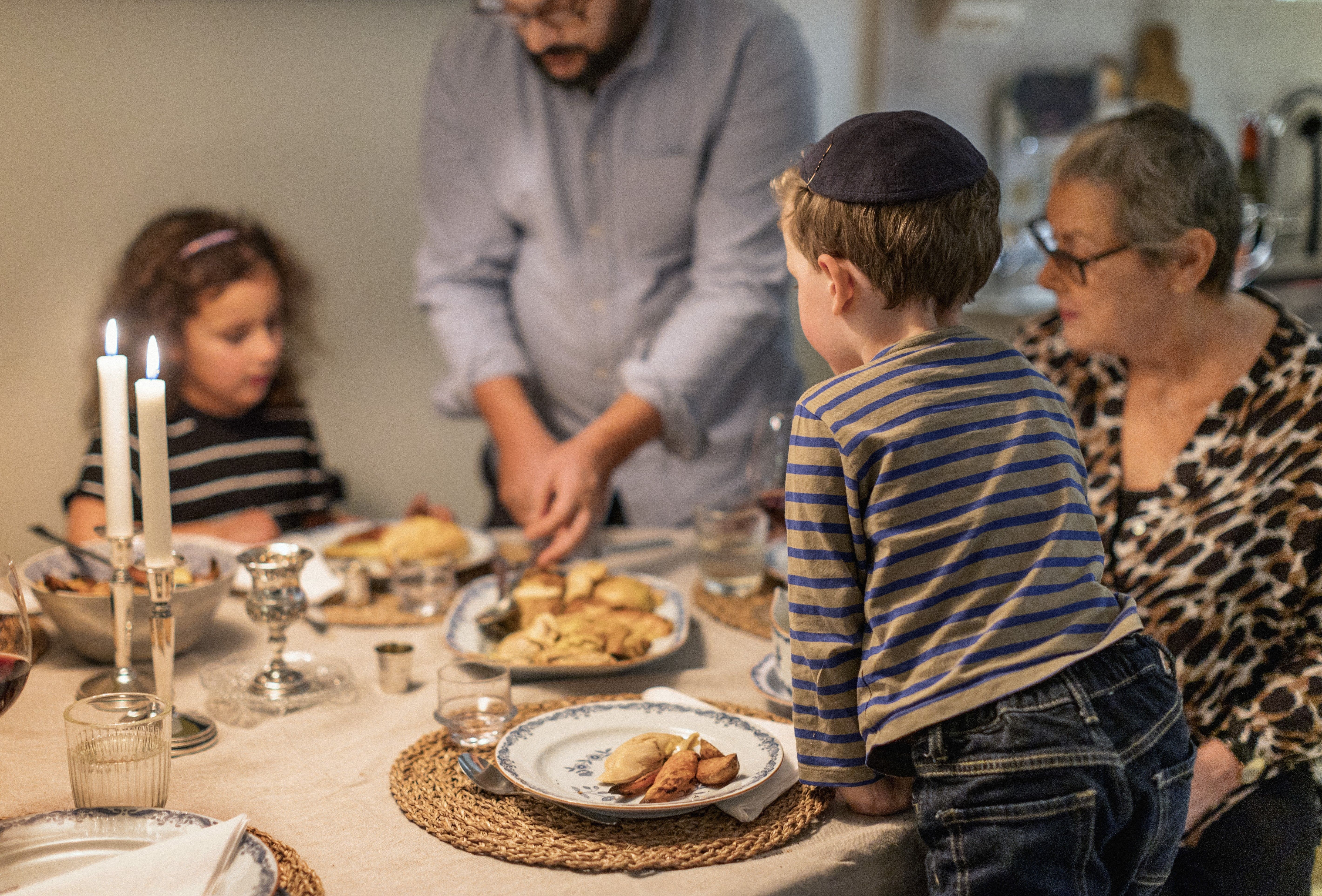 En judisk familj som har samlats för en måltid, på bordet brinner ljus.