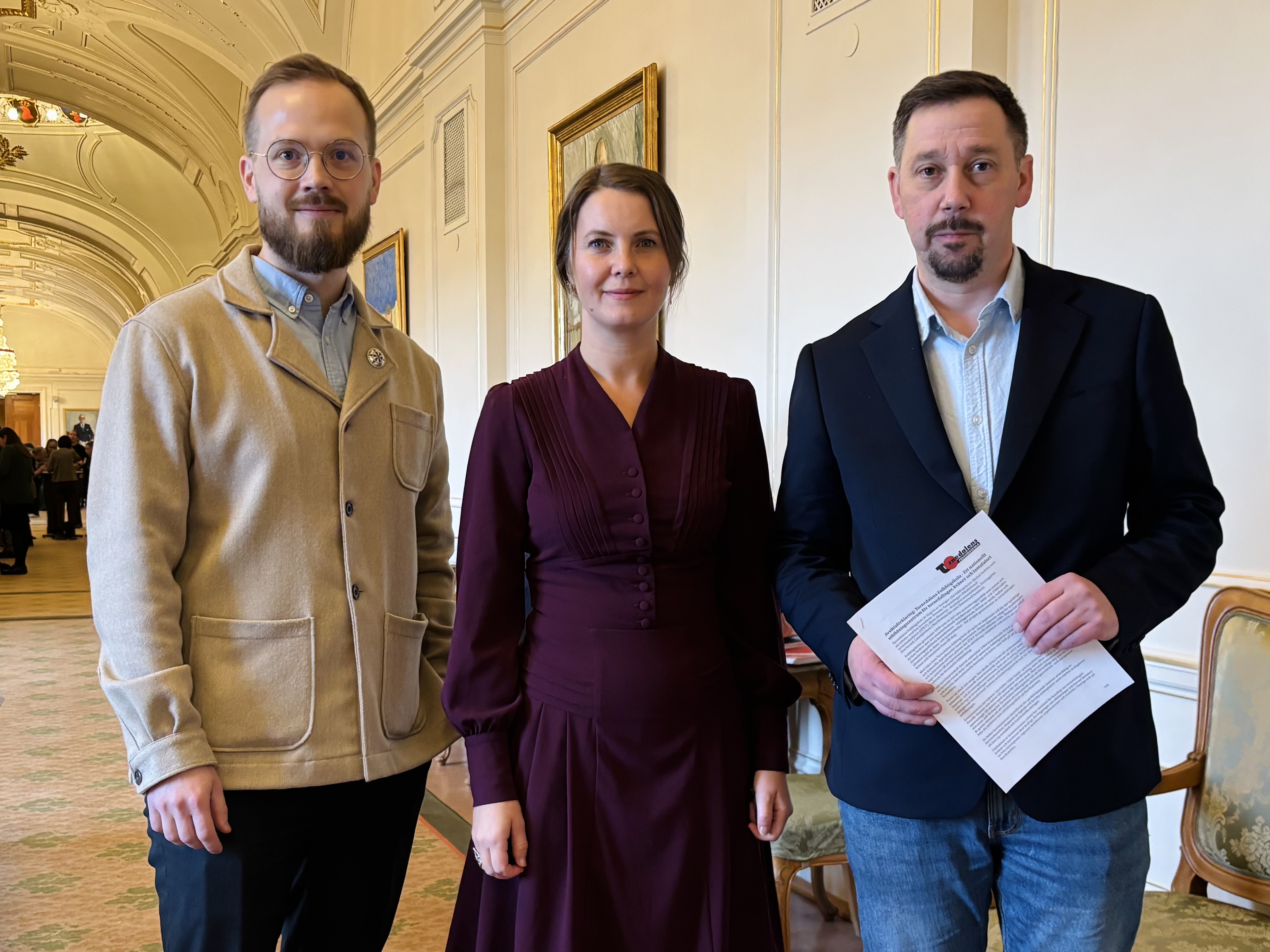 Daniel Fjellborg, Ida Karkiainen och Johan Taavo står tillsammans i Riksdagen. De tittar in i kameran och ser glada ut.