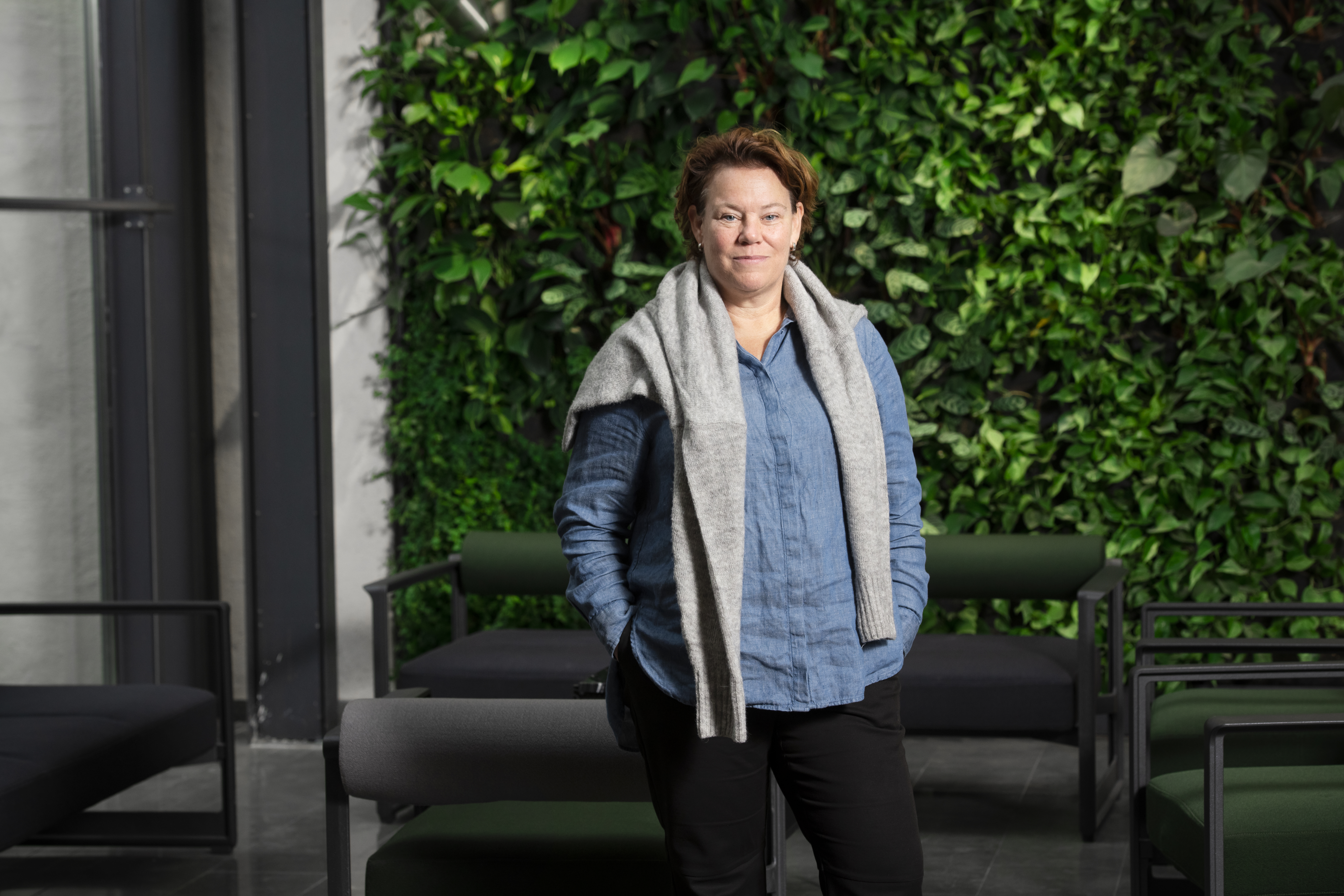 Linda Rosén, enhetschef på Folkbildningsrådet, framför grön, växtbeklädd vägg.