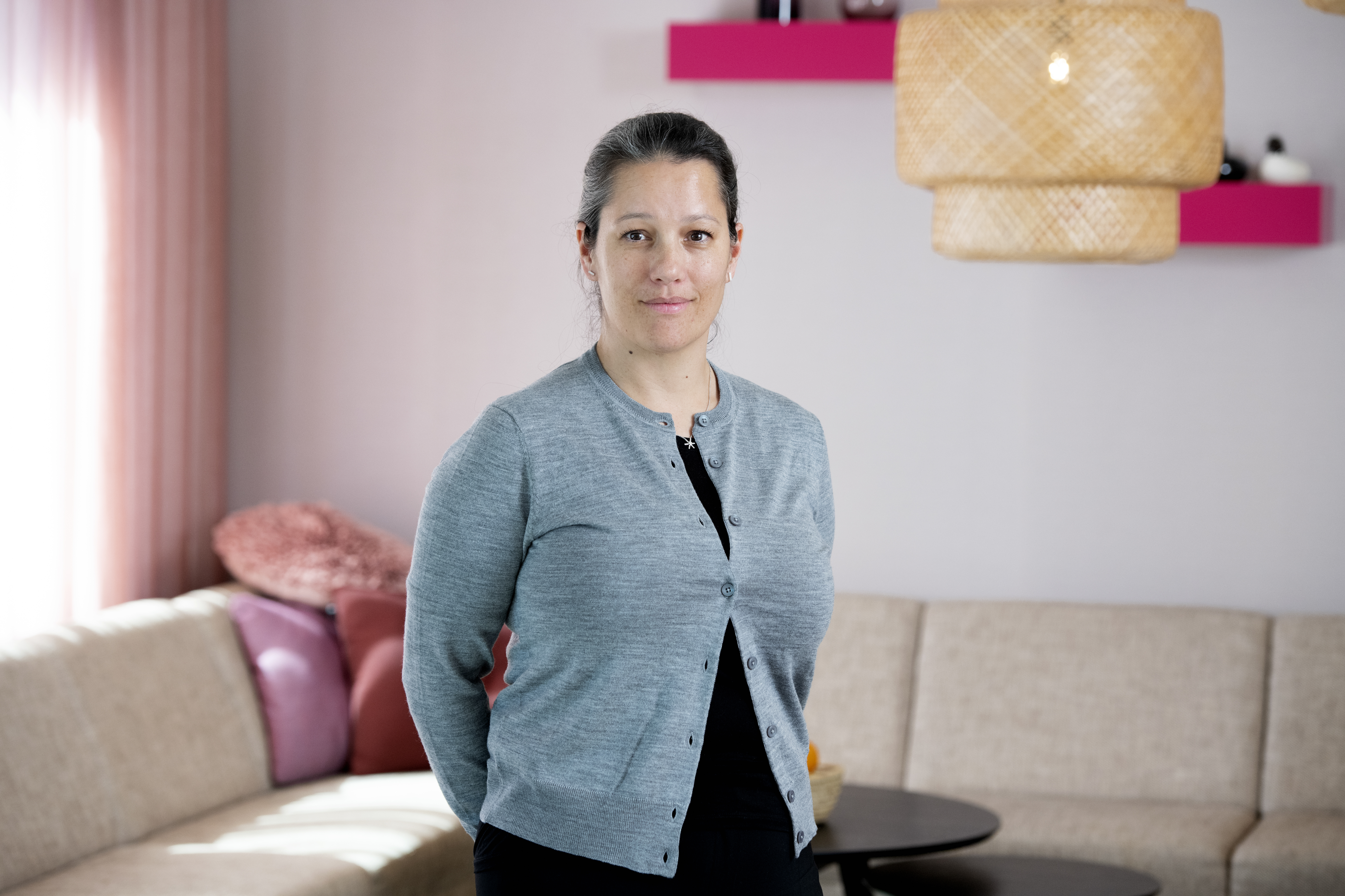 Pressbild Inger Ashing. Inger står på Folkbildningsrådets kontor framför en soffa. Hon har blå kofta på sig och tittar rakt in i kameran.